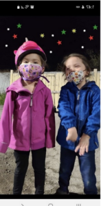 Two young children in masks looking at the camera